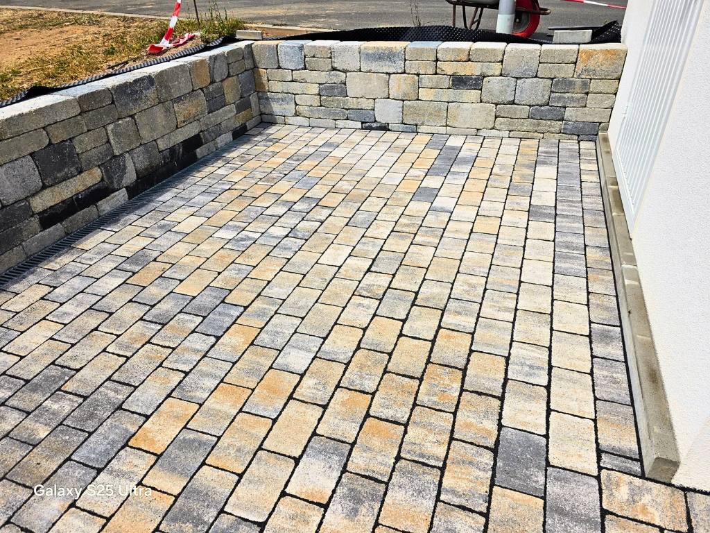 Gartenmauer aus Naturstein mit gepflastertem Vorplatz