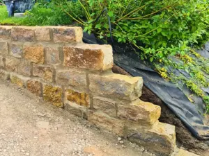 Kleinformatige Natursteinmauer mit Pflanzbereich im Garten