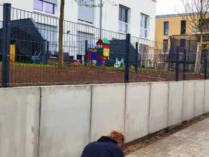 Betonmauer mit Zaun als Grundstücksbegrenzung bei Mehrfamilienhaus