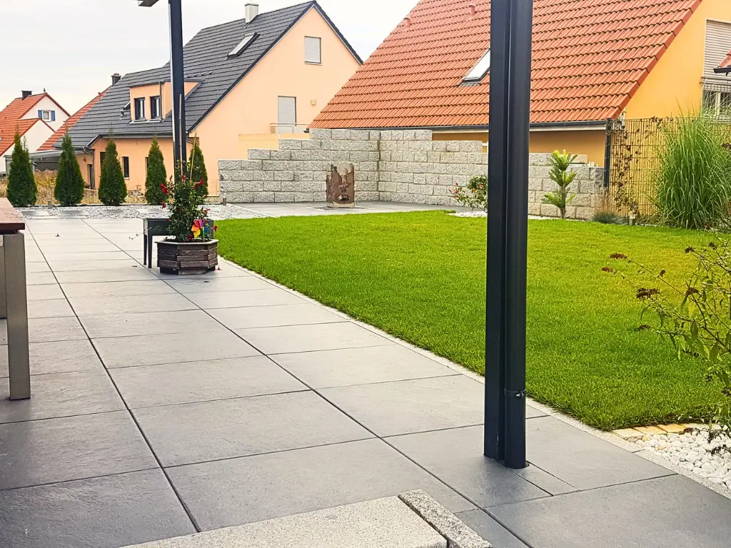 Granitmauer mit gepflegtem Rasen und moderner Terrasse
