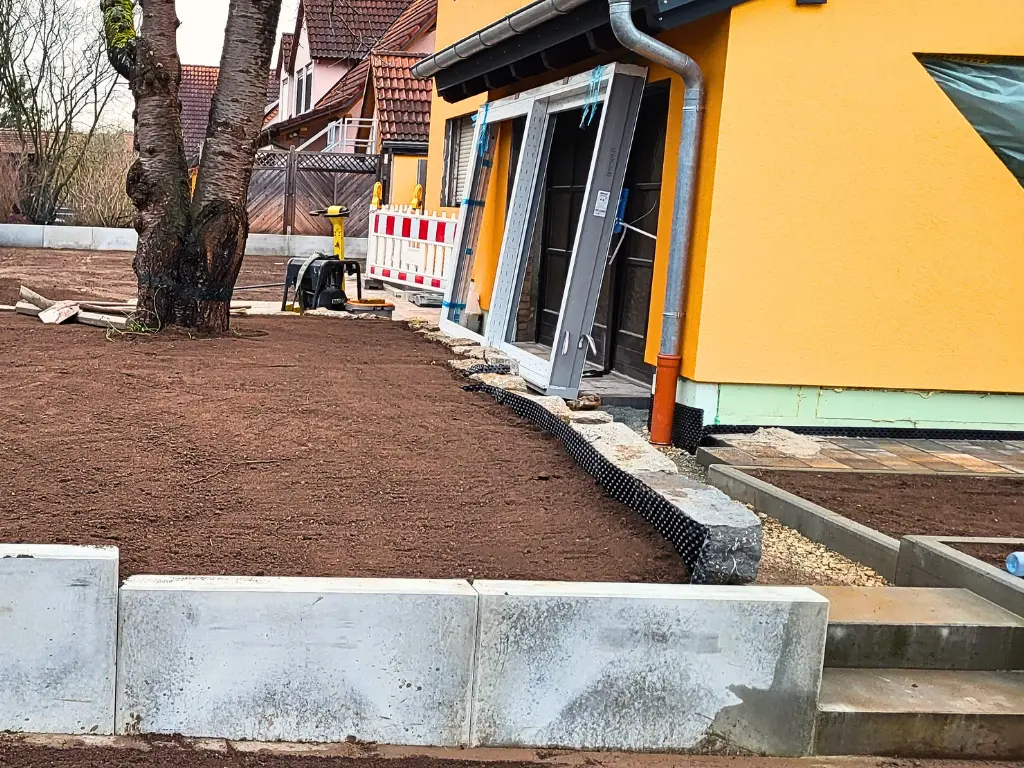Gartenmauer aus Beton-Mauerscheiben vor Neubau mit vorbereiteter Fläche