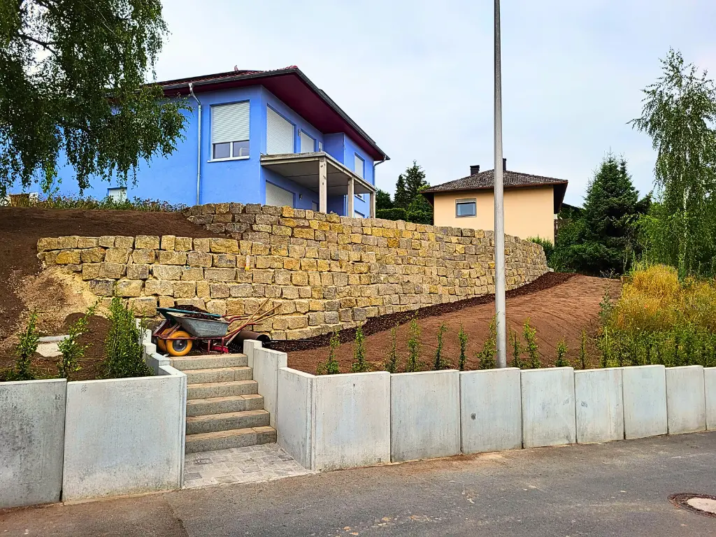 Terrassierung mit Natursteinmauer und Beton-Mauerscheiben